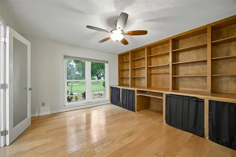 an empty room with wooden floor fan and windows