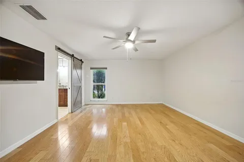 a view of an empty room with wooden floor and a window