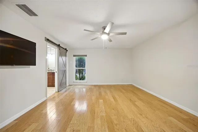 a view of an empty room with wooden floor and a window