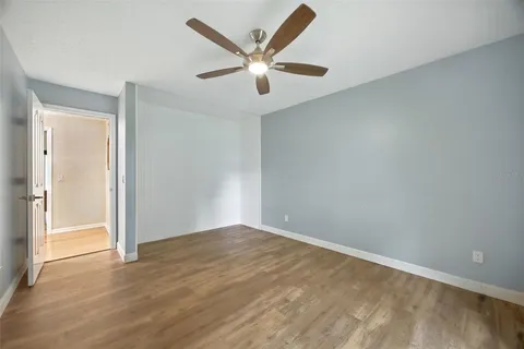 a view of empty room with wooden floor and fan