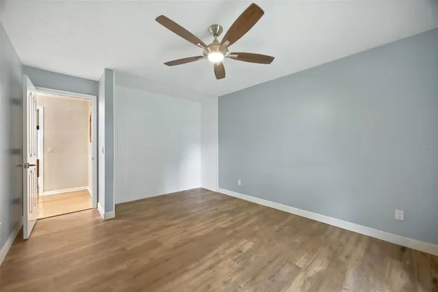 a view of empty room with wooden floor and fan