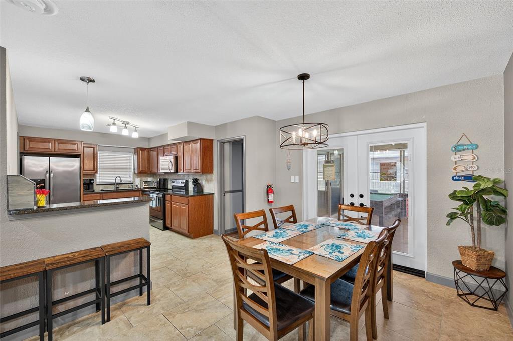 1576 Rosery Road Northeast Largo, FL 33756 - Photo 17 of 54 a dining room with wooden floor a chandelier a wooden table and chairs