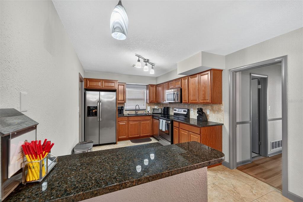 1576 Rosery Road Northeast Largo, FL 33756 - Photo 21 of 54 a kitchen with stainless steel appliances granite countertop a sink a stove and a refrigerator