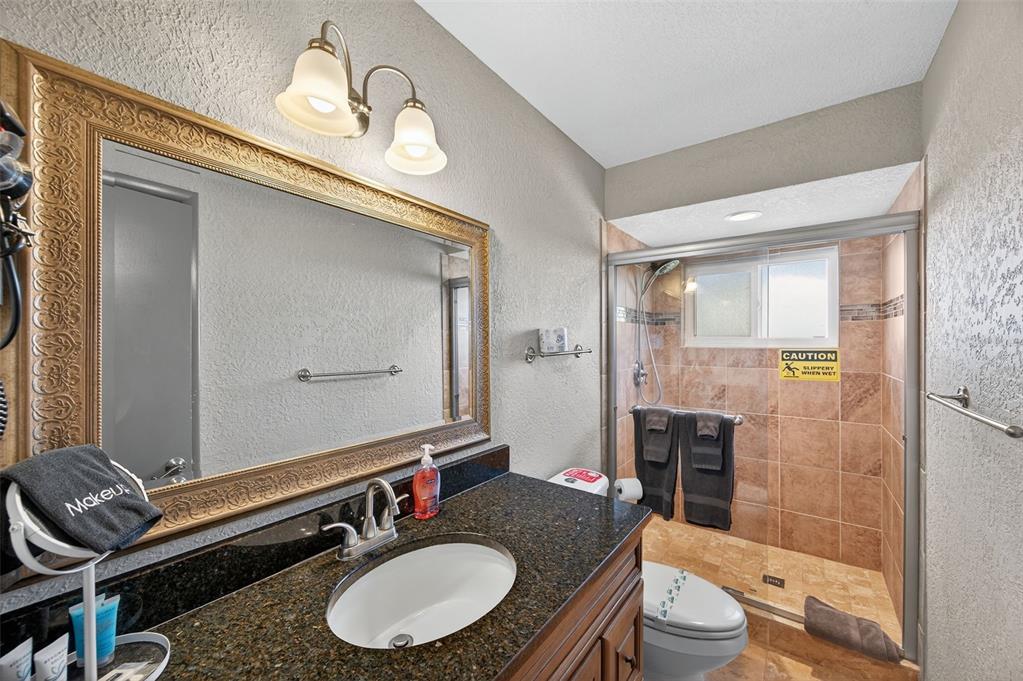 1576 Rosery Road Northeast Largo, FL 33756 - Photo 30 of 54 a bathroom with a granite countertop sink mirror vanity and toilet