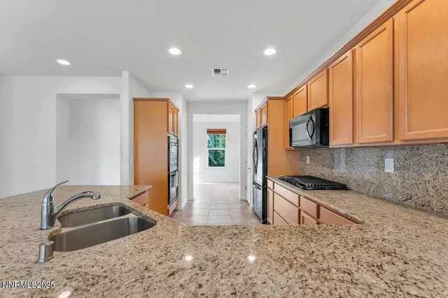 a kitchen with stainless steel appliances granite countertop a sink a stove and a refrigerator