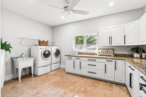 a kitchen with stainless steel appliances kitchen island granite countertop a refrigerator a stove a sink dishwasher and white cabinets with wooden floor