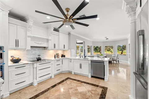 a kitchen with kitchen island a dining table chairs stainless steel appliances and cabinets