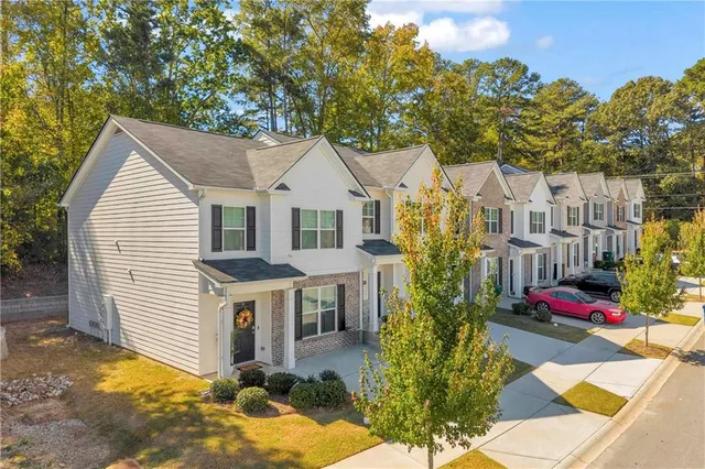 a view of a white house with a small yard and large tree