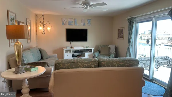 a living room with stainless steel appliances furniture a flat screen tv and a view of kitchen