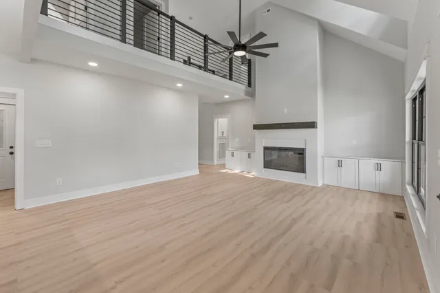 an empty room with wooden floor fireplace and windows