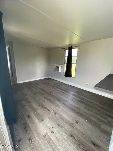 an empty room with wooden floor and window