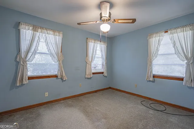 en empty room with windows and ceiling fan