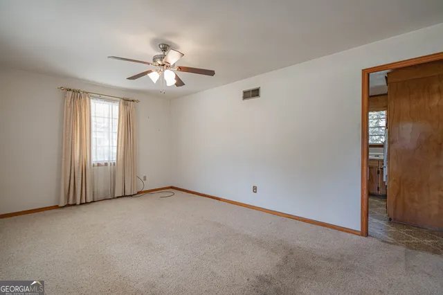 an empty room with chandelier fan and windows