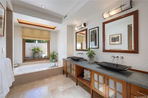 a bathroom with a double vanity sink a mirror and a bathtub
