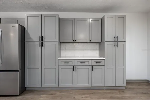 a large kitchen with stainless steel appliances a large counter top a stove a sink a refrigerator and a window