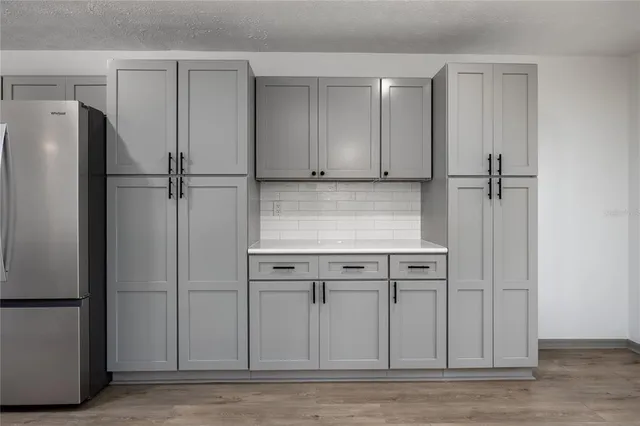 a large kitchen with stainless steel appliances a large counter top a stove a sink a refrigerator and a window