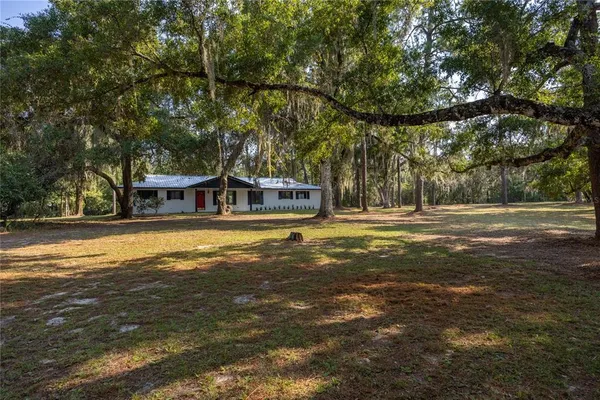 a view of a house with a big yard and large trees