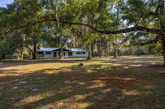 a view of a house with a big yard and large trees