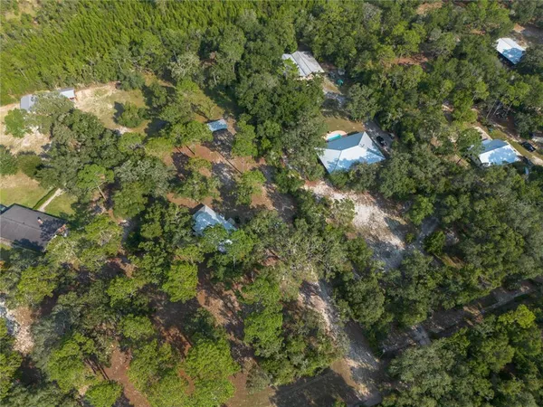 an aerial view of residential house with outdoor space and trees all around
