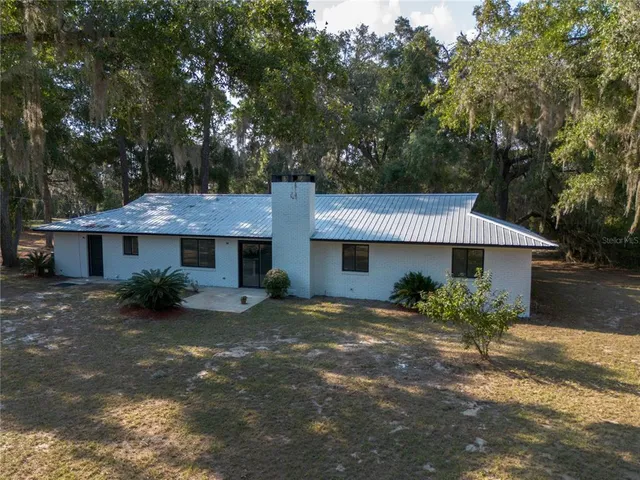 an aerial view of residential house with outdoor space and trees all around