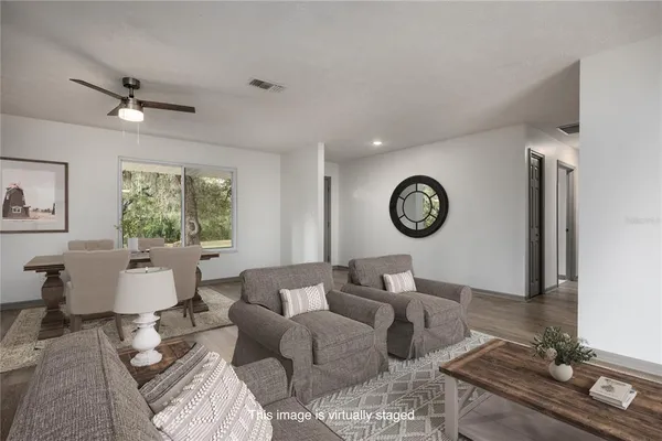 a living room with furniture kitchen view and a wooden floor