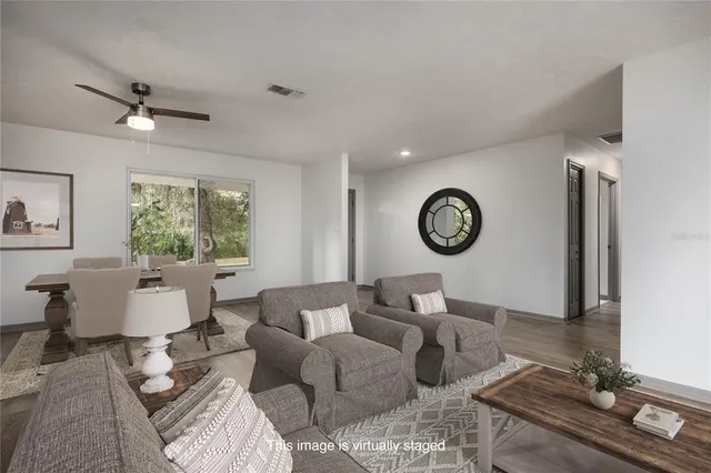 a living room with furniture kitchen view and a wooden floor