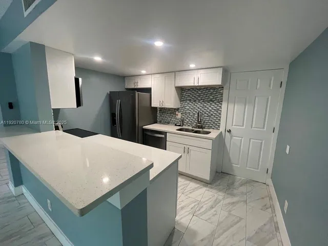 a kitchen with a white refrigerator oven a sink dishwasher and white cabinets with wooden floor