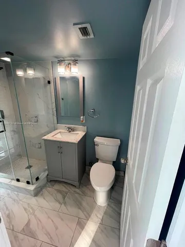 a bathroom with a granite countertop toilet sink and mirror