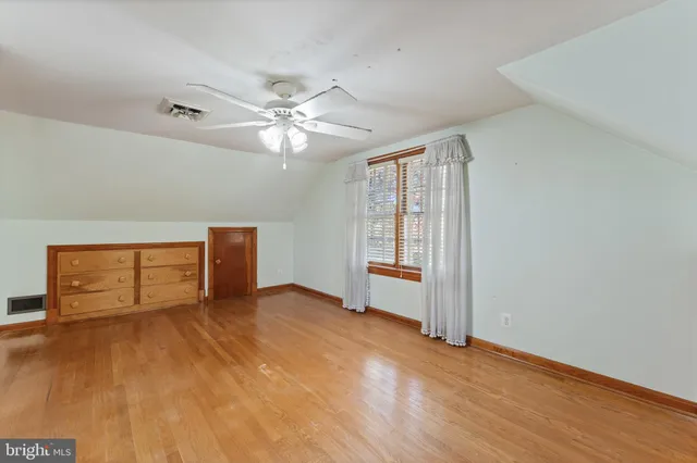 an empty room with wooden floor chandelier fan and windows