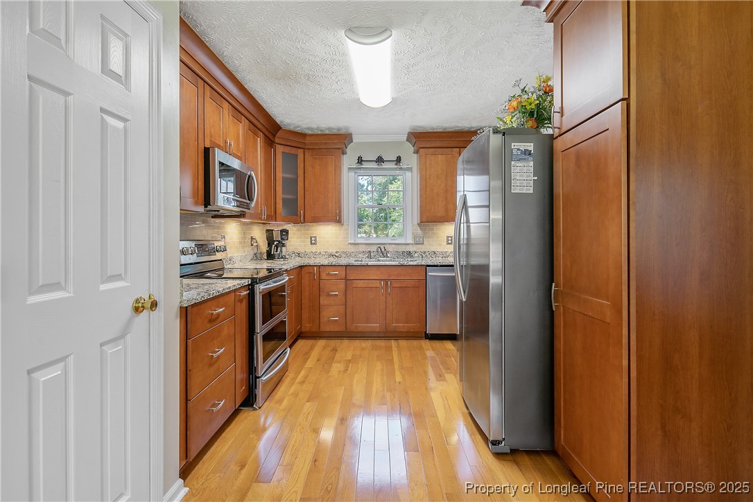 6528 Foxberry Road Fayetteville, NC 28314 - Photo 19 of 50 a kitchen with stainless steel appliances granite countertop a refrigerator a sink dishwasher a stove and white countertops with wooden floor