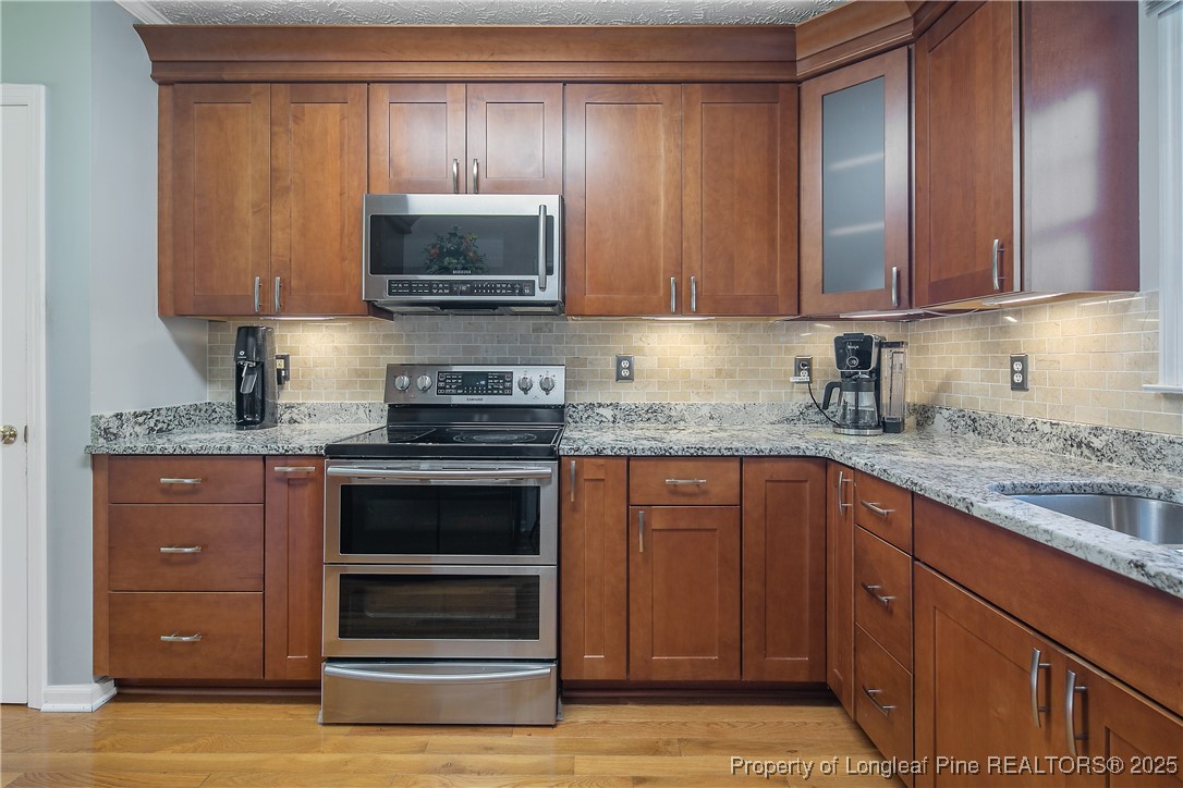 6528 Foxberry Road Fayetteville, NC 28314 - Photo 22 of 50 a kitchen with granite countertop wooden cabinets and stainless steel appliances