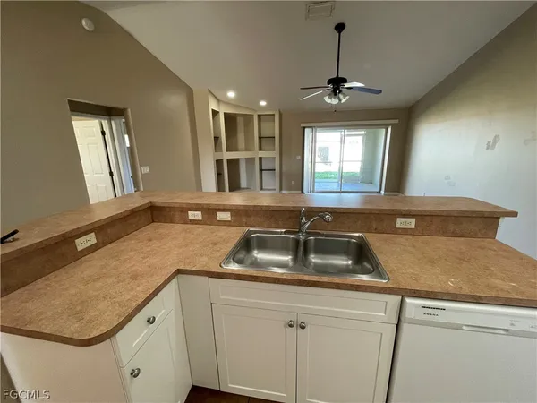 a kitchen that has a sink and a stove with wooden floor