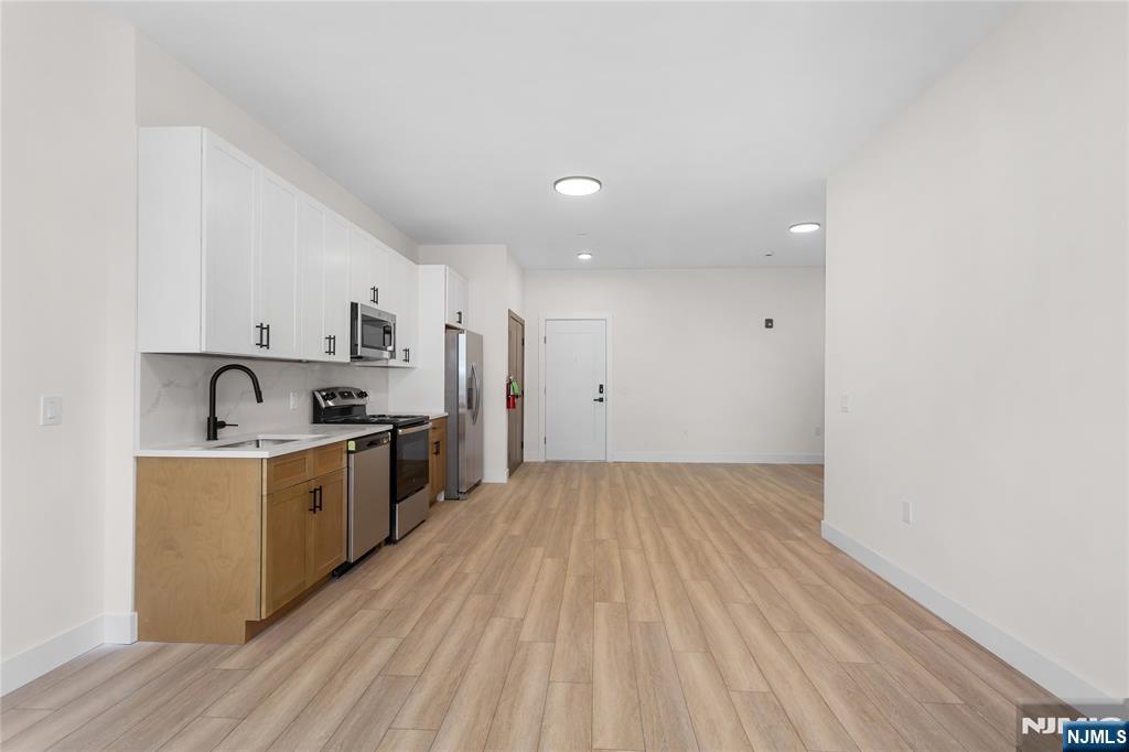 89 Mary Street, Unit 503 Paterson, NJ 07503 - Photo 4 of 14 a kitchen with stainless steel appliances a sink wooden floor and cabinets