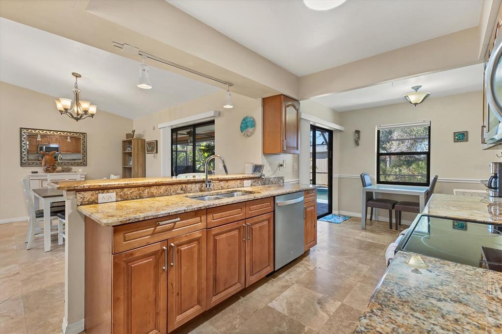 7047 Adderly Road Englewood, FL 34224 - Photo 11 of 39 a kitchen with kitchen island a stove a sink a dining table and chairs