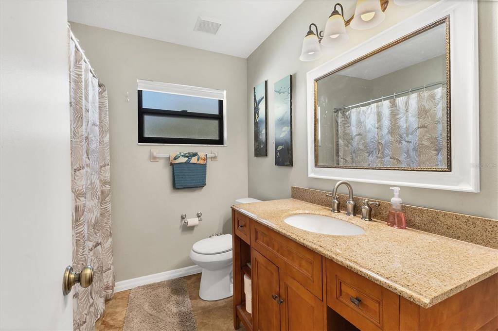 7047 Adderly Road Englewood, FL 34224 - Photo 21 of 39 a bathroom with a granite countertop sink toilet and mirror