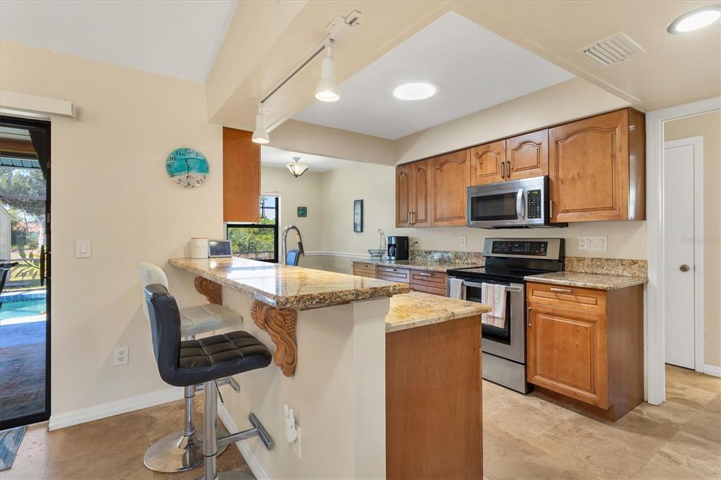 7047 Adderly Road Englewood, FL 34224 - Photo 9 of 39 a kitchen with stainless steel appliances kitchen island granite countertop a sink and cabinets