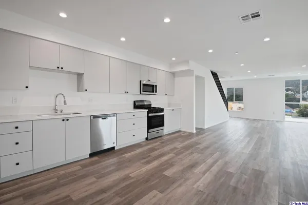 a kitchen with granite countertop white cabinets and stainless steel appliances