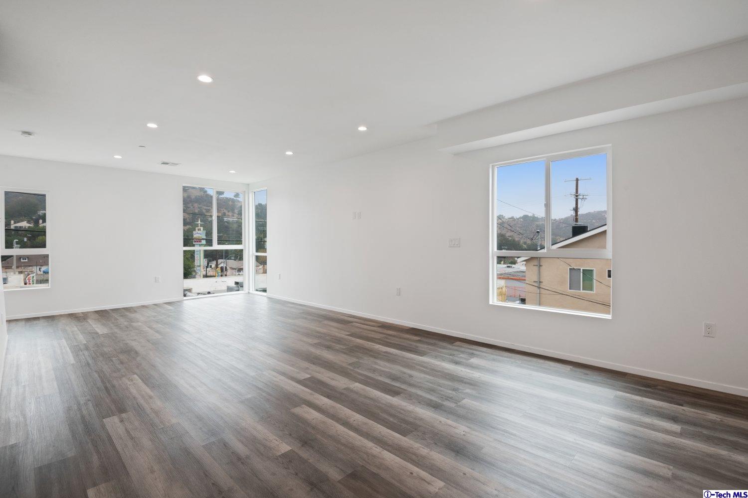 7064 Greeley Street, Unit 105 Tujunga, CA 91042 - Photo 28 of 46 a view of empty room with wooden floor and kitchen view