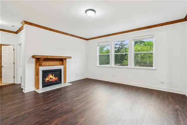 an empty room with wooden floor fireplace and windows