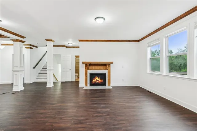 a view of an empty room with wooden floor fireplace and a window