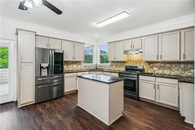 a kitchen with stainless steel appliances granite countertop a refrigerator stove a sink and dishwasher with wooden floor