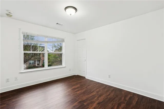 an empty room with wooden floor and windows