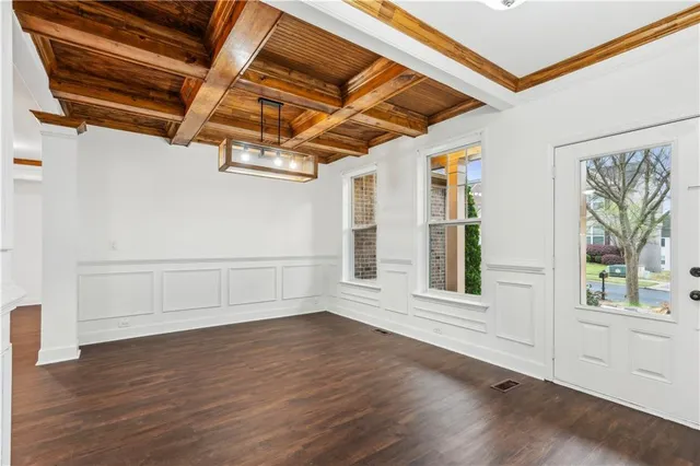 a view of an empty room with wooden floor and windows