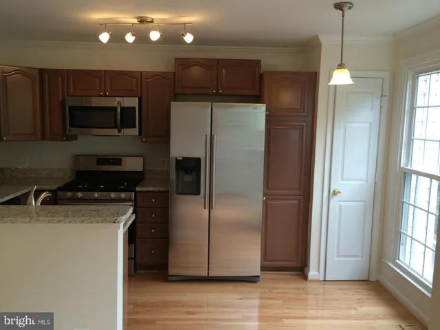 a kitchen with stainless steel appliances granite countertop a refrigerator a sink and a stove