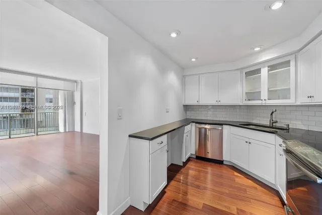 a kitchen with granite countertop a stove a sink and a refrigerator