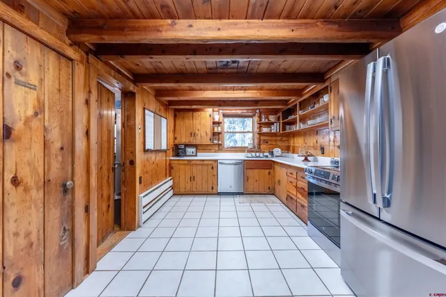 a large white kitchen with a sink a refrigerator and cabinets