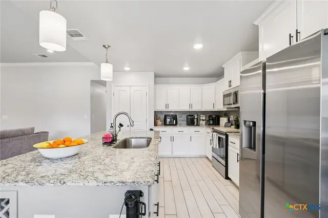 a kitchen with stainless steel appliances granite countertop a sink a stove and refrigerator