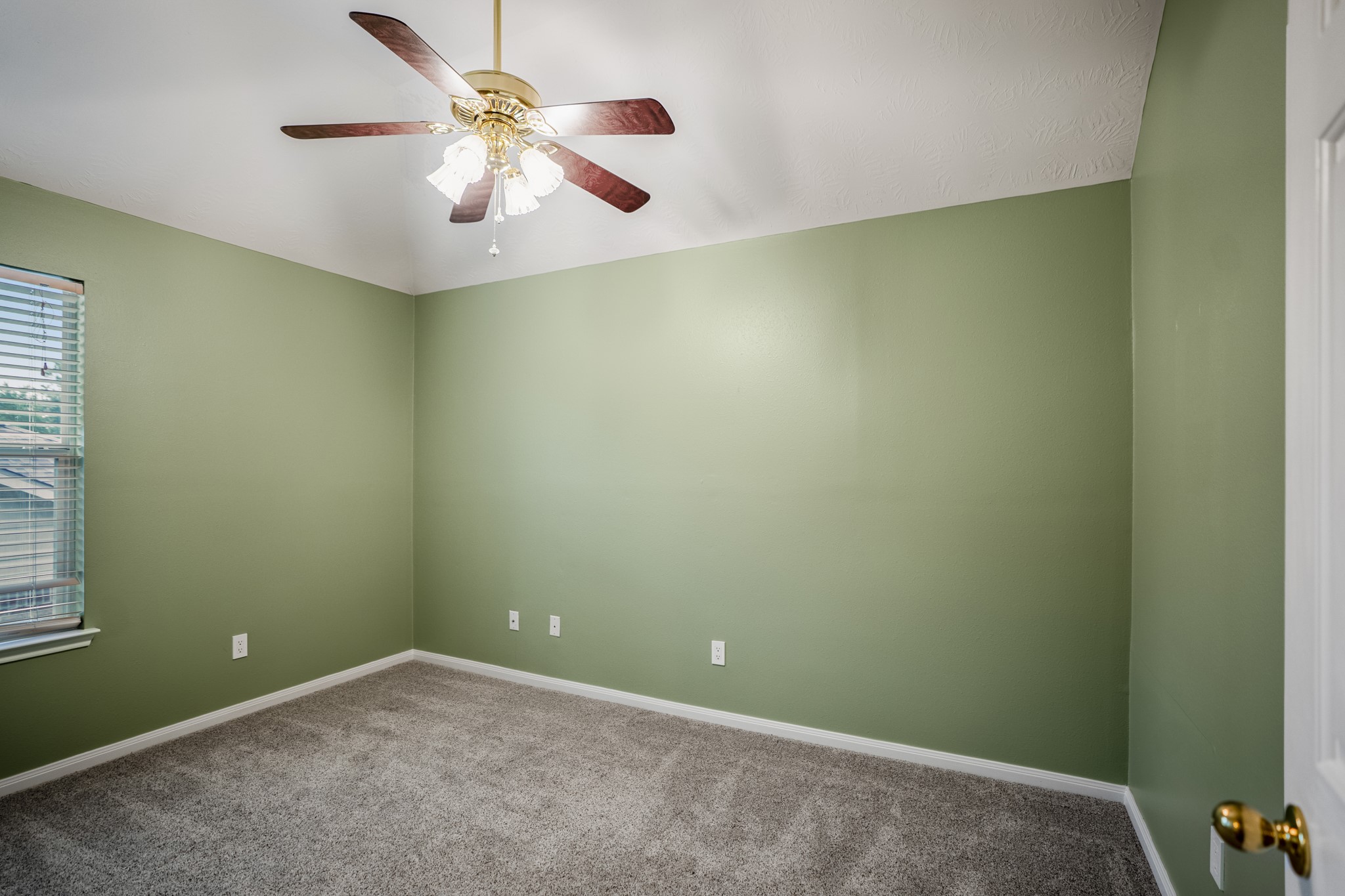 6311 Sparrows Glen Lane Spring, TX 77379 - Photo 29 of 50 The third bedroom upstairs offers a vaulted ceiling, ceiling fan, soft carpet, and window light along one side, with closet access near the entry for a clean, practical layout.