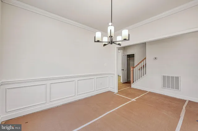 a view of an empty room with window and chandelier fan