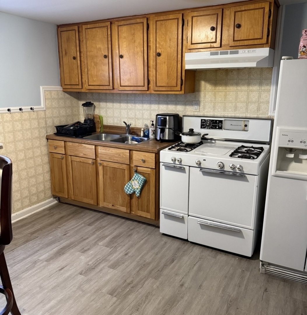 3704 West 58th Street Chicago, IL 60629 - Photo 9 of 12 a kitchen with wooden cabinets and a stove top oven